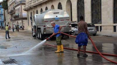 Dos hombres limpian una calle aledaña al Gran Teatro de La Habana. Foto: EFE.