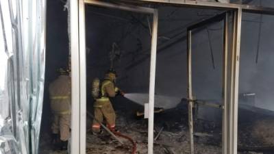Elementos del cuerpo de bomberos extinguen el incendio provocado en un importante centro comercial de Choloma.