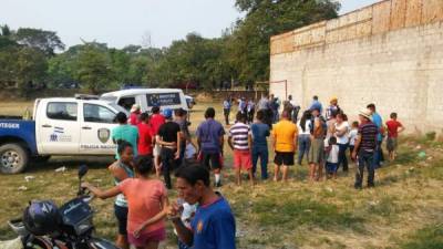 Un grupo de personas rodea la escena del crimen en la colonia El Paraíso del sector Rivera Hernández de San Pedro Sula, zona norte de Honduras.
