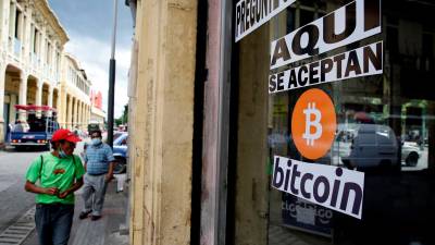 Apuesta. Salvadoreños circulan cerca de una tienda que acepta el bitcóin como medio de pago en la capital de ese país.