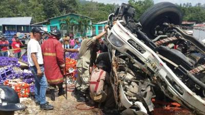Los bomberos de Santa Cruz de Yojoa rescatan a las personas atrapadas en el camión que volcó.