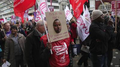 Un manifestante en Londres muestra un cartel en el que se lee: “Este es el rostro de una persona infeliz por los recortes a las pensiones”.