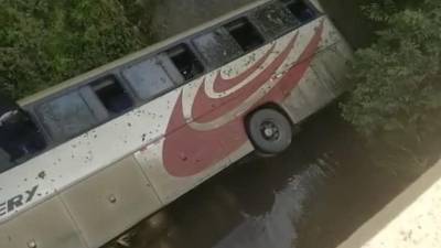 Fotografía que muestra el autobús de la empresa Discovery volcado tras caer desde un puente en Honduras.