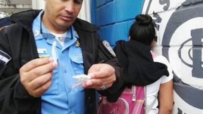 Agente de la Policía muestra la droga decomisada a la estudiante.