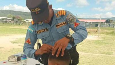 Miembro de la Policía Nacional corta el cabello de un niño en Intibucá.