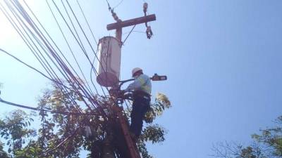 Un técnico de la Enee realiza trabajos en un poste del tendido eléctrico.