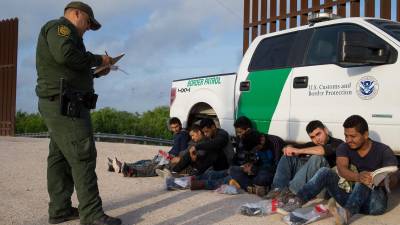 Un agente de la Patrulla Fronteriza detienen a un grupo de inmigrantes indocumentados en la frontera.