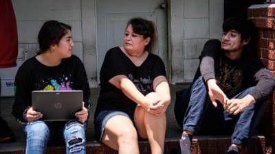 Yesenia Alcerro, una sobreviviente del Covid-19, conversa con sus hijos, Astrid y Jackson Ocampo, en las escaleras frente a su casa ubicada en un barrio al este de Houston, Texas. EFE