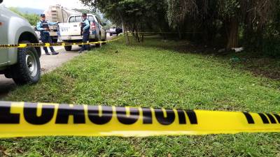 Plolicías alrededor de la escena del crimen a orilla del Segundo Anillo Periférico de San Pedro Sula.