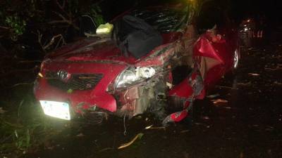 Vehículo Toyota Corolla aplastado por un árbol en Atlántida, Honduras.
