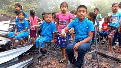 Niños de la comunidad de San Isidro sentados en la sillas que se quemaron.