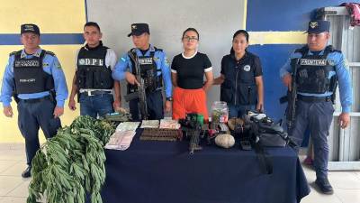 Fotografía muestra el momento en que autoridades presentan a la fémina capturada junto a la droga, dinero, municiones y armas decomisadas.
