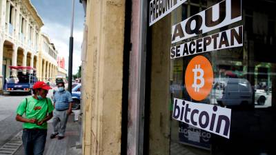 Apuesta. Salvadoreños circulan cerca de una tienda que acepta el bitcóin como medio de pago en la capital de ese país.