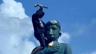 Venezolano encima de la estatua de Hugo Chávez.
