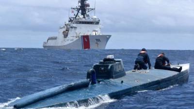 A Spanish Guardia Civil's diver stands over the refloated prow of a submarine used to transport drugs illegally in Aldan, northwestern Spain, on November 26, 2019. - Police in Spain have seized a submarine, about 20 metres (65 feet) long, loaded with several tonnes of cocaine off the coast of the northwestern region of Galicia which arrived from South America, officials said today. Two Ecuadorian men were arrested as part of the operation yesterday in the seaside town of Cangas near the border with Portugal. (Photo by Lalo R. VILLAR / AFP)