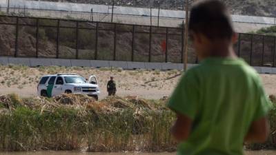 A Mexican boy looks at a member of the US Border Patrol standing guard on the border between El Paso in the United States and Ciudad Juarez in Mexico, on July 22, 2014. Texas Governor Rick Perry on Monday announced plans to send 1,000 military reservists to the state's border with Mexico, to tackle a surge in immigrant children flooding into the United States. AFP PHOTO/Jesus Alacazar