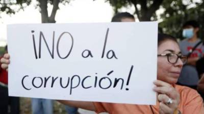 Hondureña sostiene una hoja de papel con la leyenda “¡No a la corrupción!”.