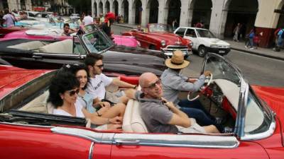 Los turistas pasean por los autos clásicos que abundan en la isla.