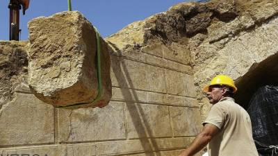 Trabajadores trasladando las piedras que sellaban la entrada de una tumba frente a dos esfinges cerca de la antigua Anfípolis.