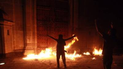 Un grupo de manifestantes incendia las puertas del Palacio Nacional de México.