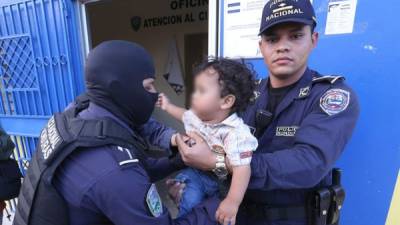 Policías sostienen al niño de dos años.
