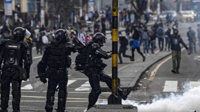 Un policía antidisturbios patea un bote de gas lacrimógeno durante una protesta contra el gobierno del presidente colombiano Iván Duque, en Bogotá, el 23 de noviembre de 2019. El primer toque de queda de Colombia en décadas convirtió a su capital en un pueblo fantasma nervioso, como personas armadas con machetes, murciélagos y cuchillos protegían las puertas contra los saqueadores encapuchados que se creía que se estaban volviendo locos.