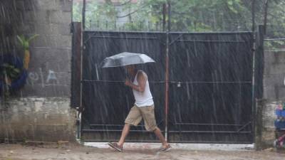 Foto de archivo de un hondureño caminado bajo la lluvia.