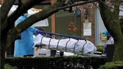 Los trabajadores de la salud transportan un cuerpo a un camión refrigerante que sirve como depósito de cadáveres temporal en el Centro Médico Judío Kingsbrook, en Brooklyn, Nueva York. Foto EFE