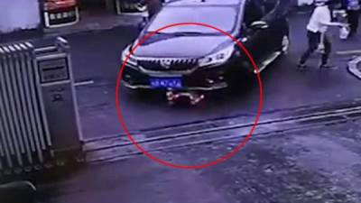 El automóvil tumba a la niña y pasa sobre ella mientras la madre está distraída con su bebida.