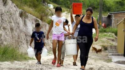 Habitantes de la comunidad periférica El Manzanal regresan a sus casas con recipientes llenos de agua (para cocinar) que obtuvieron en La Fuente.
