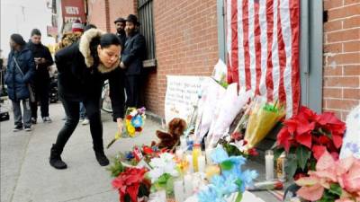 Un mujer fue registrada este domingo lamentar el asesinato de dos policías de la ciudad de Nueva York, en una calle de Brooklyn, luego de que fueran tiroteados en su patrulla por un afroamericano que luego se suicido. EFE