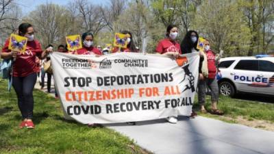 Un grupo de mujeres inmigrantes sostiene una pancarta que pide detener la deportación de inmigrantes, otorgar la ciudadanía para todos y una recuperación del covid para todos. EFE