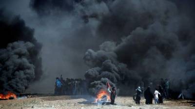 Palestinians burn tyres as they clash with Israeli forces near the border between the Gaza strip and Israel, east of Gaza City on May 14, 2018, following the the controversial move to Jerusalem of the United States embassy. Fifty-two Palestinians were killed by Israeli fire during violent clashes on the Gaza-Israel border coinciding with the opening of the US embassy in Jerusalem, the health ministry in the strip announced. / AFP PHOTO / THOMAS COEX