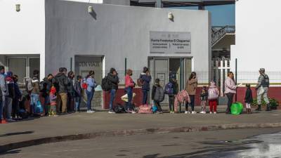 Grupos de migrantes hacen fila para cruzar a Estados Unidos y continuar con su proceso de asilo a través de la garita internacional del Chaparral en Tijuana.