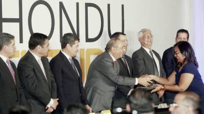 El presidente Juan Orlando Hernández observa al empresario Camilo Atala entregar la beca a una beneficiaria.