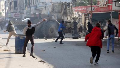 Palestinos lanzan piedras en medio de enfrentamientos con tropas israelíes durante una incursión en Yenín, Cisjordania, este 26 de enero.