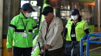 Empleados municipales utilizan mascarillas como medida de protección en una estación de buses. Foto: AFP