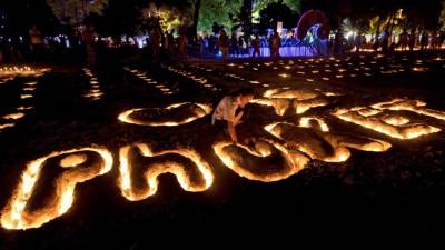 Una estudiante tailandés coloca velas en una escultura de arena durante las conmemoraciones del décimo aniversario del tsunami de 2004 en la playa de Patong, en la provincia de Phuket.