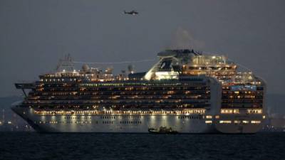 A small boat is pictured next to the Diamond Princess cruise ship with over 3,000 people as it sits anchored in quarantine off the port of Yokohama on February 4, 2020, a day after it arrived with passengers feeling ill. - Japan has quarantined the cruise ship carrying 3,711 people and was testing those onboard for the new coronavirus on February 4 after a passenger who departed in Hong Kong tested positive for the virus. (Photo by STR / JIJI PRESS / AFP) / Japan OUT