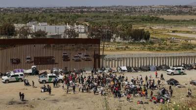 Decenas de migrantes reunidos en un punto fronterizo entre México y Estados Unidos.