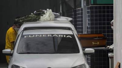 Dos hombres trasladan un ataúd a un coche fúnebre en el hospital Evandro Freire de Río de Janeiro (Brasil). EFE/ Antonio Lacerda/Archivo