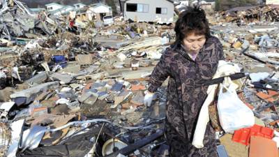 A woman searches through the rubble of her home destroyed in Friday's powerful earthquake-triggered tsunami in Ofunato, Iwate prefecture, northern Japan, Sunday, March 13, 2011. (AP Photo/Kyodo News) JAPAN OUT, MANDATORY CREDIT, NO SALES IN CHINA, HONG KONG, JAPAN, SOUTH KOREA AND FRANCE