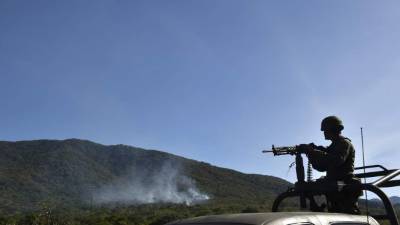 Un militar patrulla la zona donde los narcotraficantes derribaron un helicóptero del ejército mexicano.