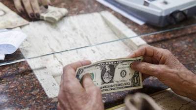 Un usuario cobra sus remesas en dólares en una institución bancaria.