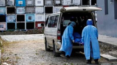 Trabajadores de los servicios funerarios con equipo de protección trasladan el cuerpo de una persona fallecida con síntomas de COVID-19, en Quezon City, Manila. Foto EFE