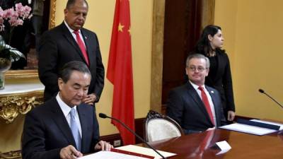 Chinese Foreign Minister Wang Yi (L) reads a document next to his Costa Rican counterpart Manuel Gonzales (R) and Costa Rica's President Luis Guillermo Solis (C) during the signing of an agreement on economic and technical cooperation at the Costa Rican Foreign Ministry in San Jose on September 15, 2017 / AFP PHOTO / EZEQUIELBECERRA