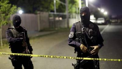 Dos agentes salvadoreños custodian una escena del crimen. Foto de archivo.