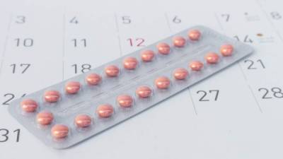 Close up birth-control pill with date of calendar background, health care and medicine concept