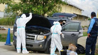 Especialistas en inspecciones oculares revisando un vehículo tipo camioneta robada que fue usada por delincuentes durante un tiroteo en San Pedro Sula.