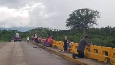 Adultos, jóvenes y niños se arrodillaron en el puente sobre el canal Maya.